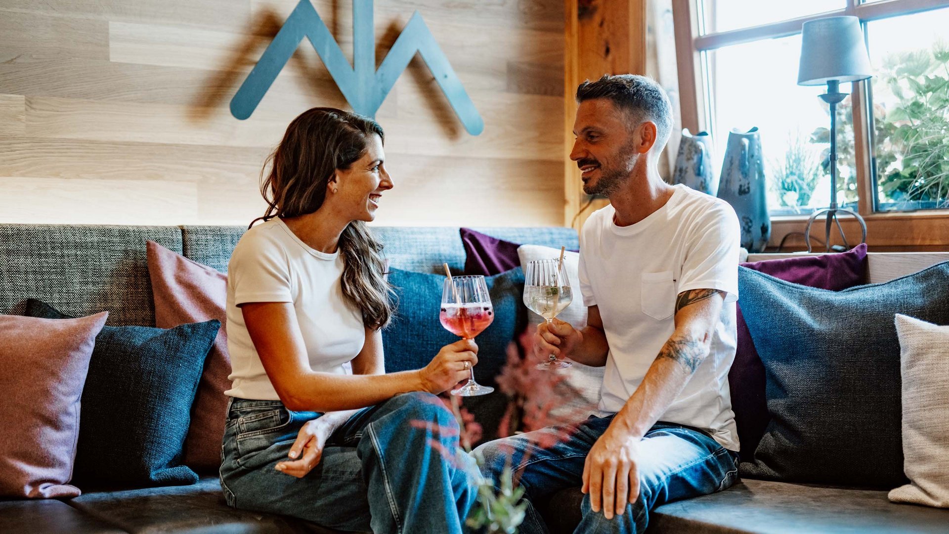 Couple sitting on sofa toasting with drinks in cozy setting