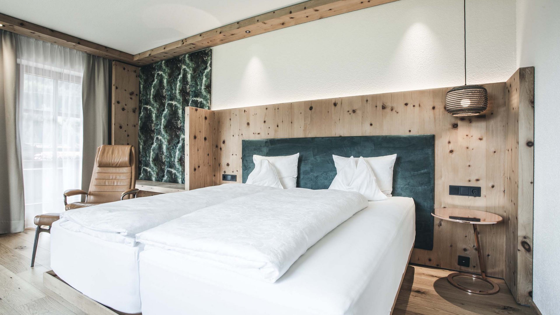 Modernes Schlafzimmer mit Doppelbett, Holzverkleidung und Sessel